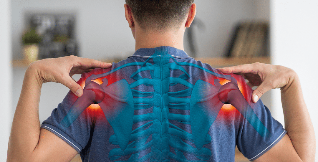 Rear view of a man in a blue shirt touching both shoulders with highlighted red areas indicating pain points in the shoulders.