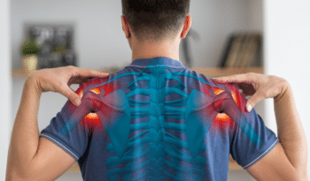 Rear view of a man in a blue shirt touching both shoulders with highlighted red areas indicating pain points in the shoulders.