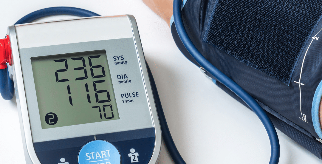 Blood pressure monitor displaying a reading of 230/116 on a patient's arm.