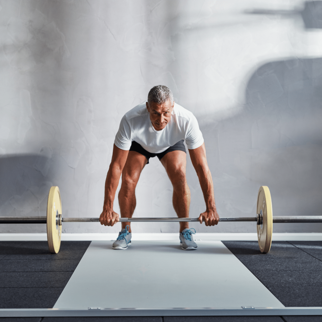 Man lifting weights to strengthen his posterior chain for managing and preventing lower back pain.