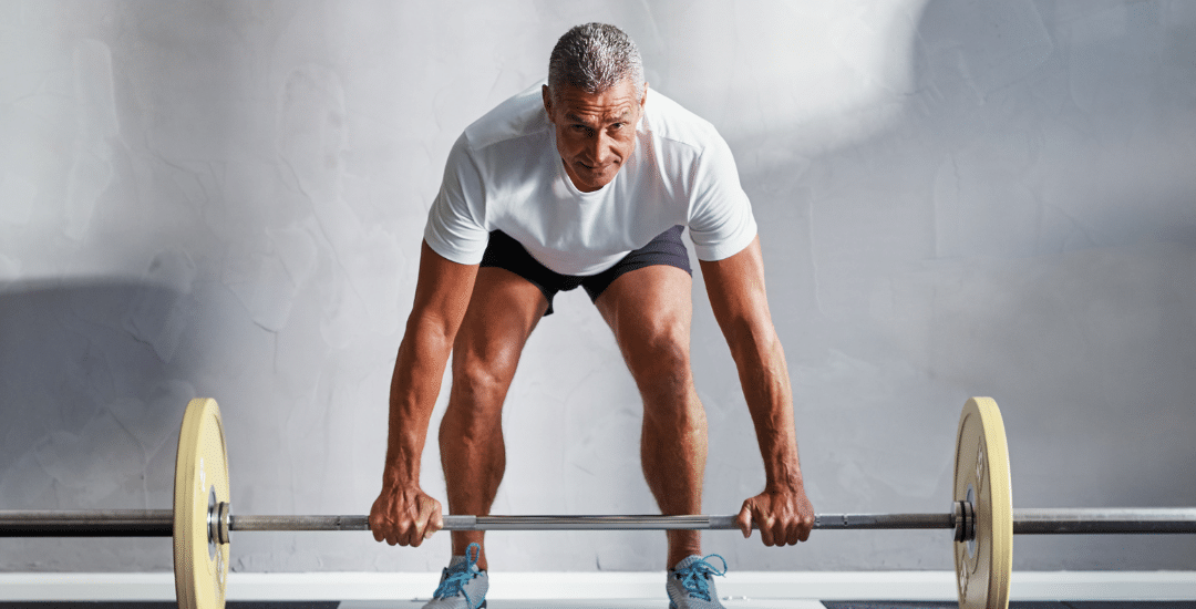 Man lifting weights to strengthen his posterior chain for managing and preventing lower back pain.