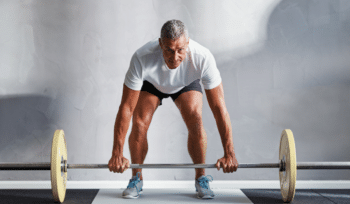 Man lifting weights to strengthen his posterior chain for managing and preventing lower back pain.