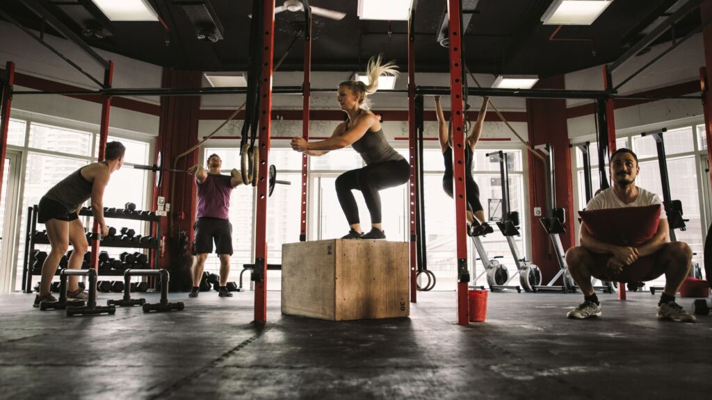 Group of five people engaging in functional training exercises in a dynamic workout class, focused on building strength, mobility, and everyday movement skills.