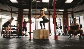 Group of five people engaging in functional training exercises in a dynamic workout class, focused on building strength, mobility, and everyday movement skills.