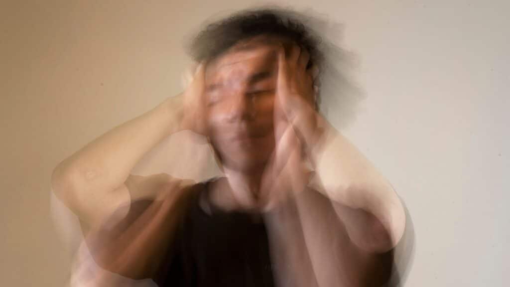 A man holding his head in frustration, with blurred motion conveying stress and anxiety.