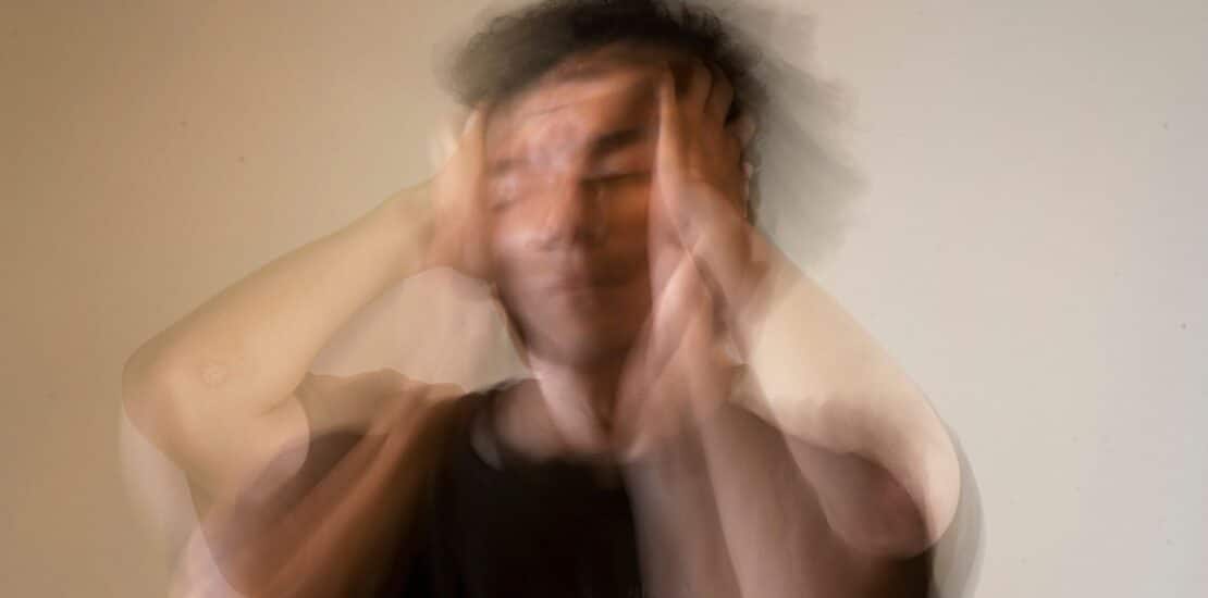 A man holding his head in frustration, with blurred motion conveying stress and anxiety.